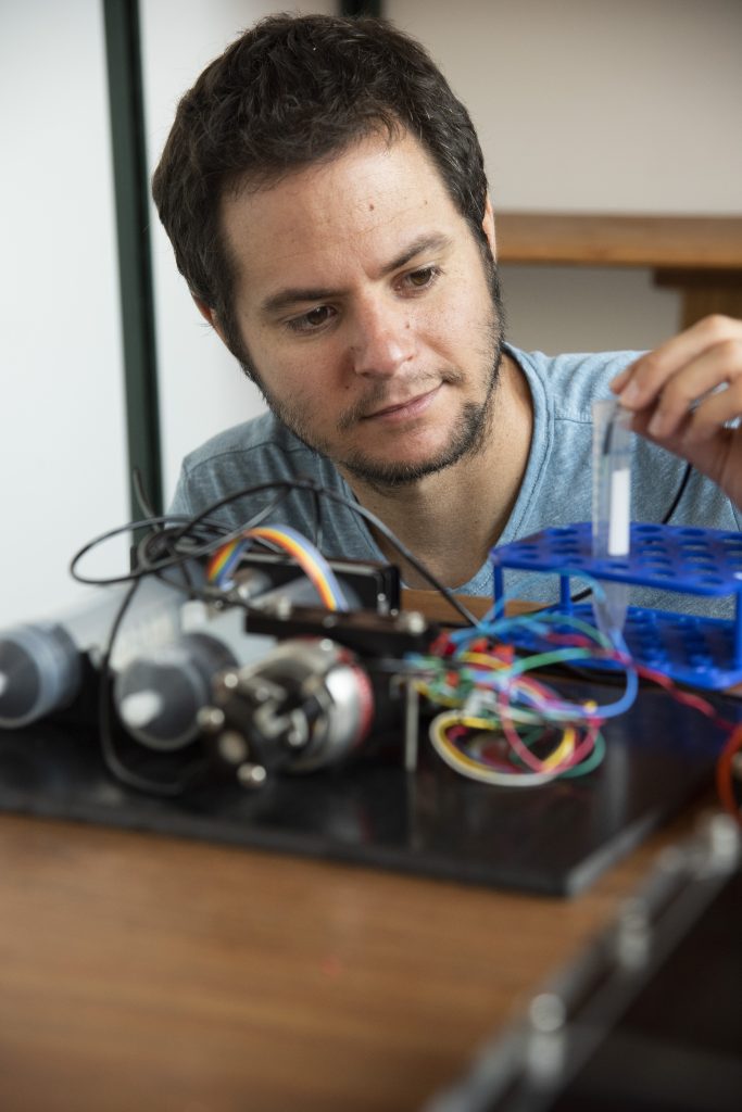 engineer works on an open sensor with different colored wires in the foreground